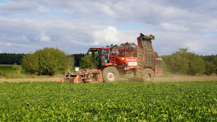 Red harvesting machine working in a green field.